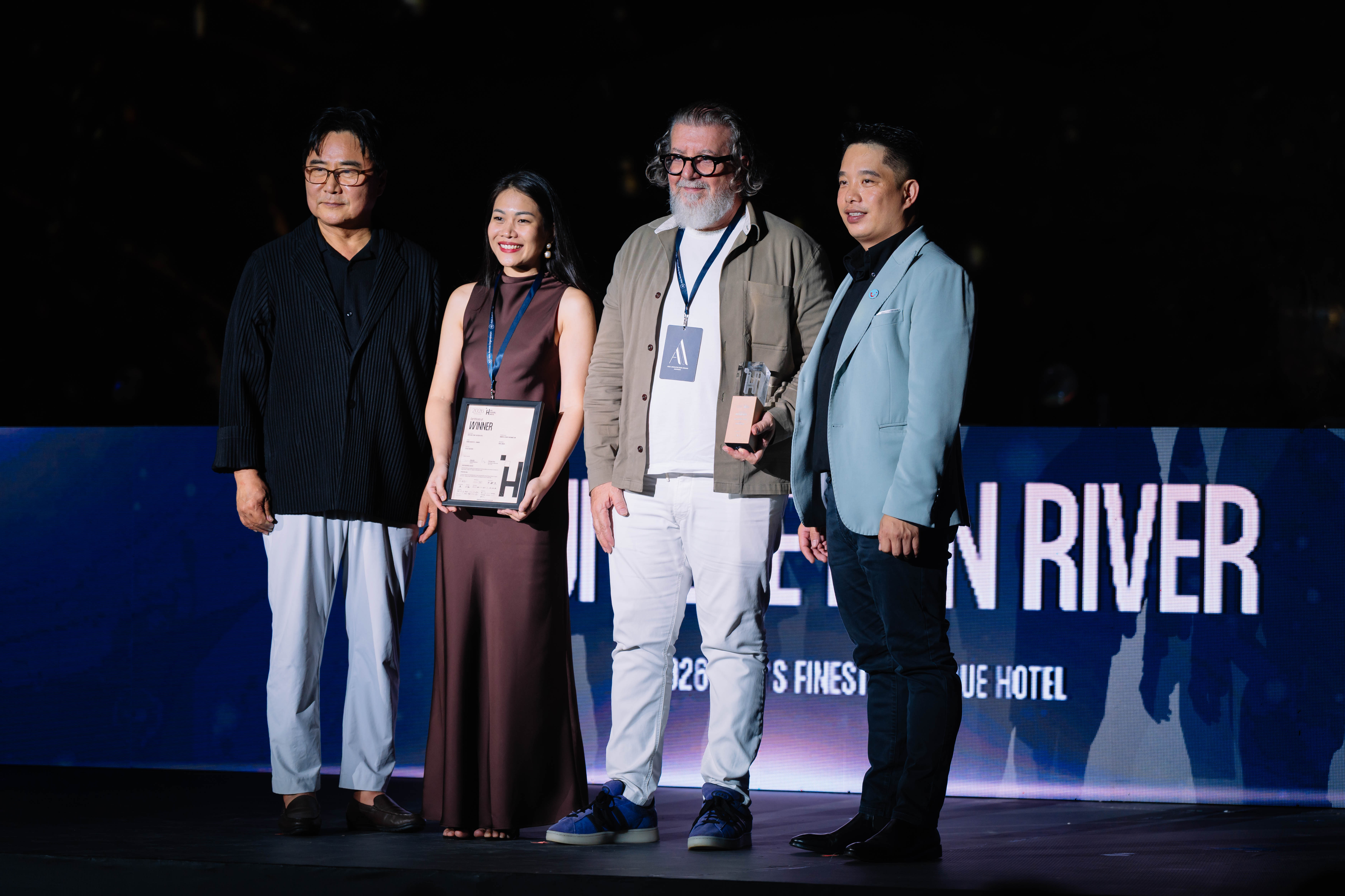 Four people on stage with a hospitality award certificate at the 2026 Asia Hospitality Awards