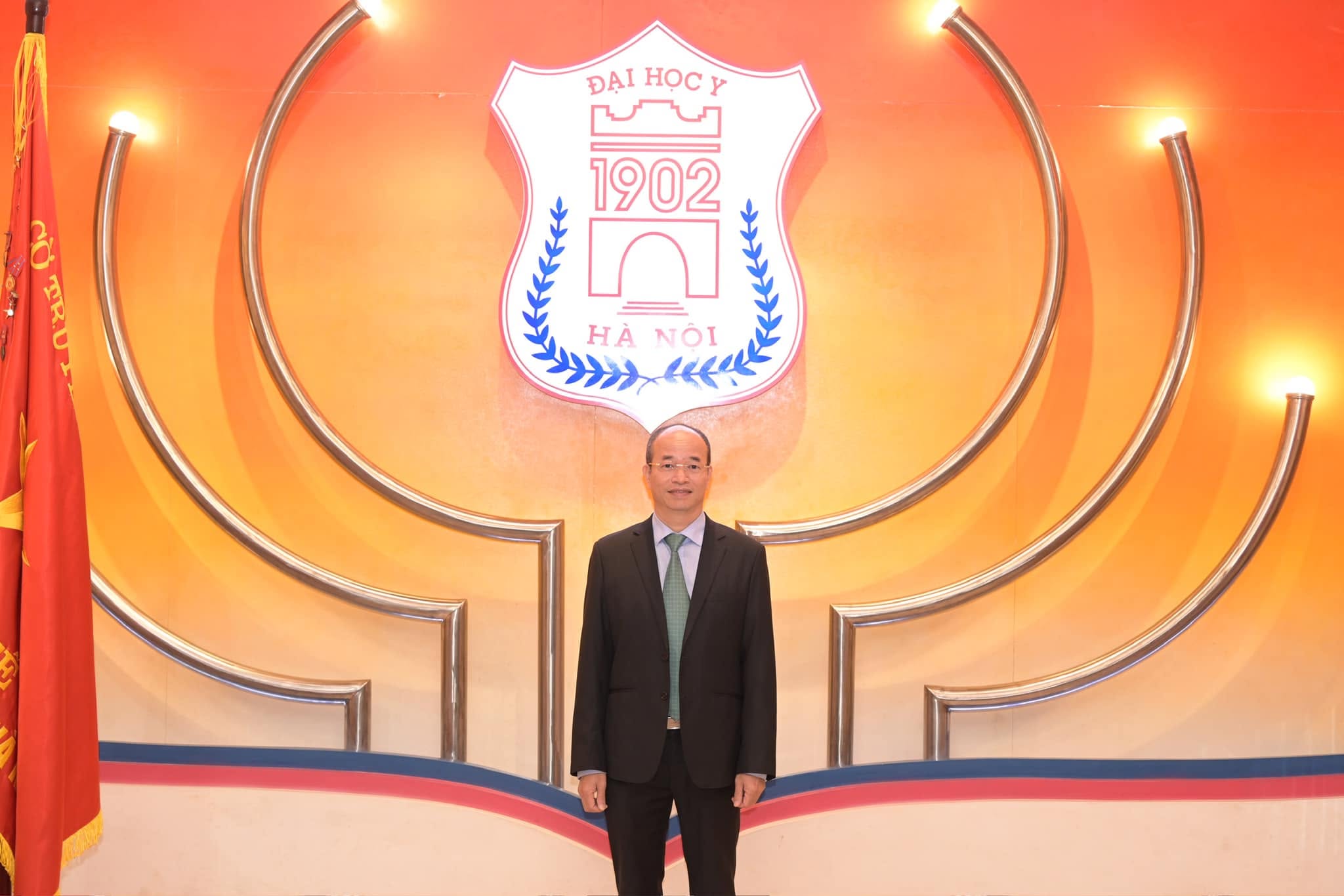Do Duy Cuong stands before the emblem of Hanoi Medical University.