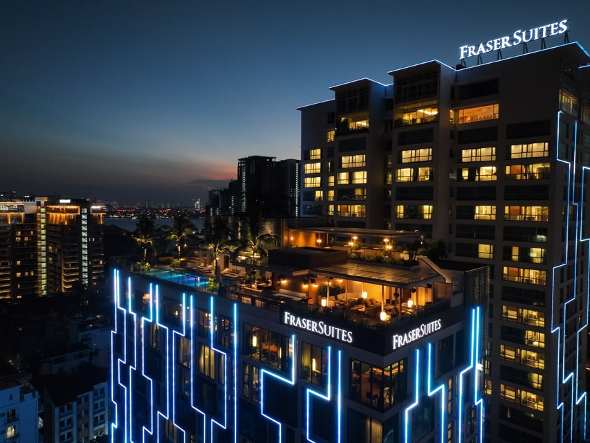 Fraser Suites Hanoi exterior at dusk, with rooftop pool and blue-lit facade above West Lake