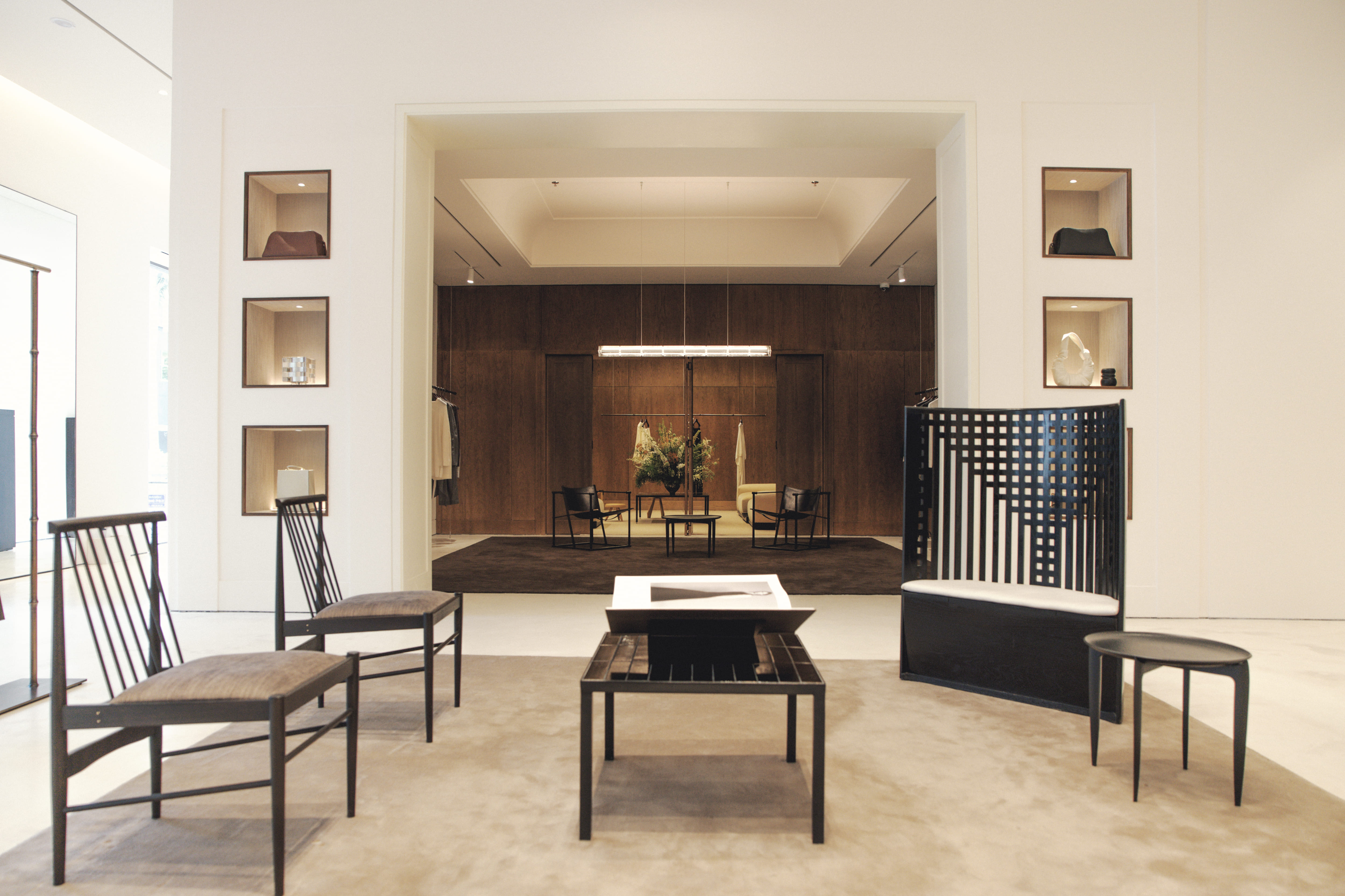 The minimalist interior of the Gia Studios boutique, with handbags in display niches and a wood-panelled room beyond