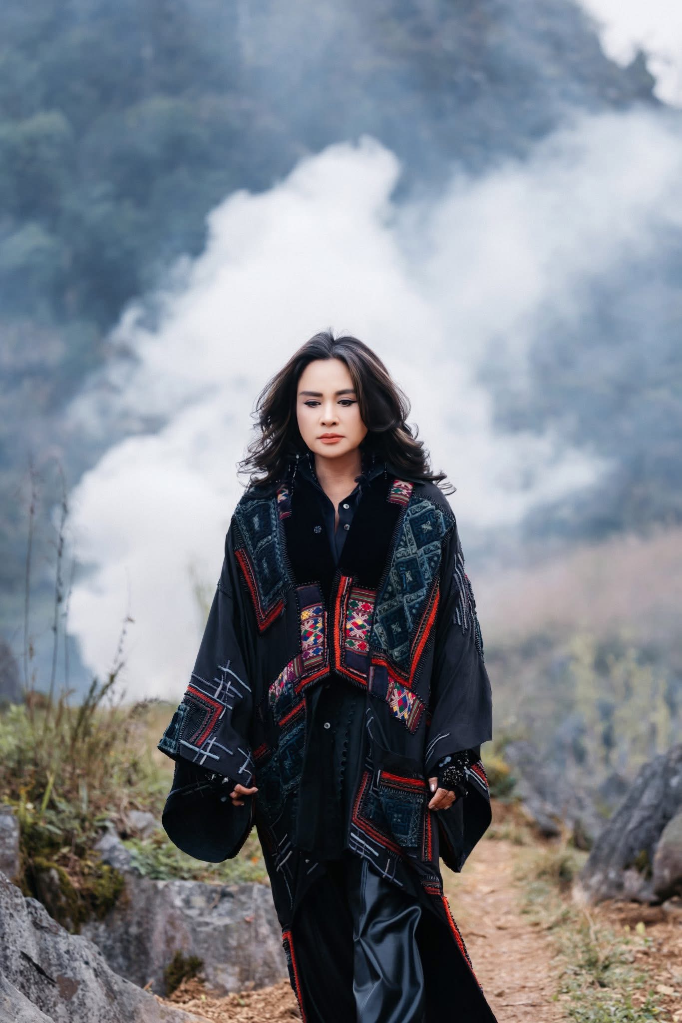Thanh Lam in a black brocade coat, walking through mountains