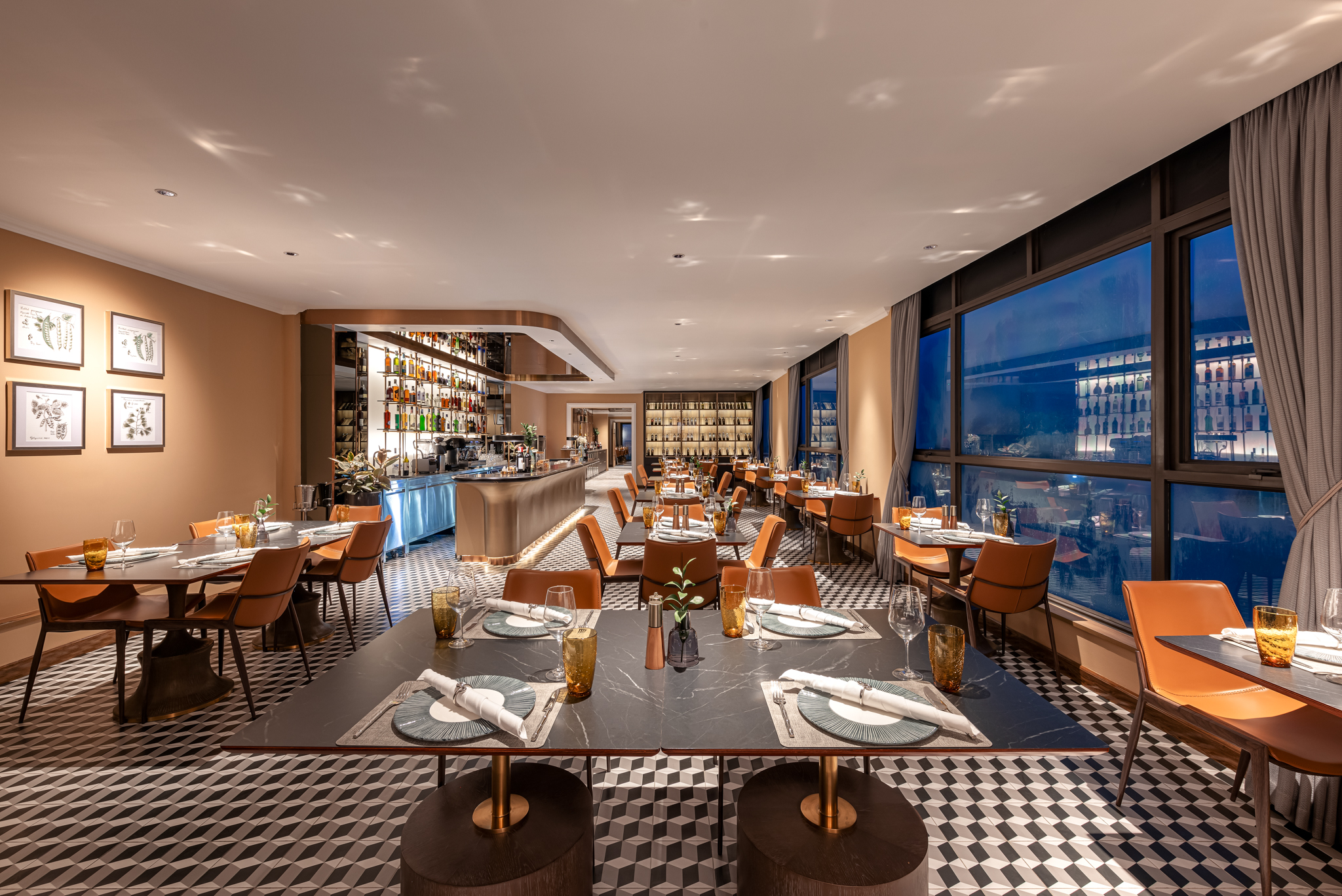 A restaurant and bar at La Siesta with orange leather chairs and a checkerboard floor, with a city view at dusk