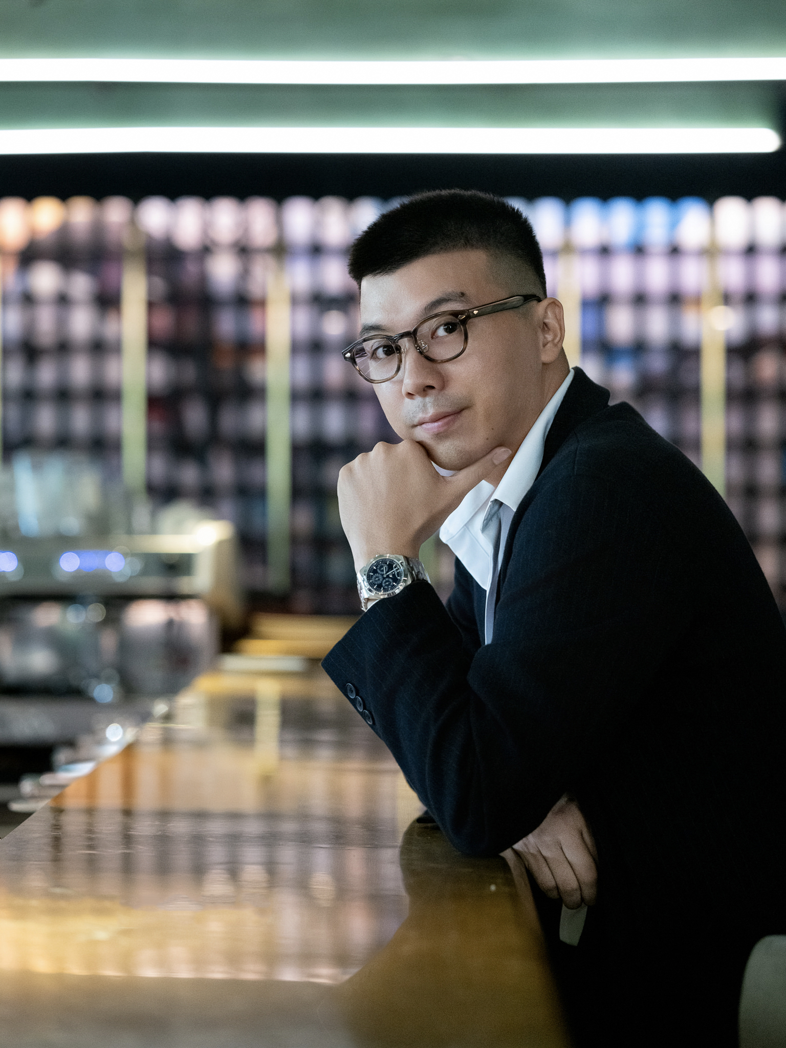 A portrait of the photographer Chu Viet Ha in a dark jacket, resting his chin on his hand at a bar