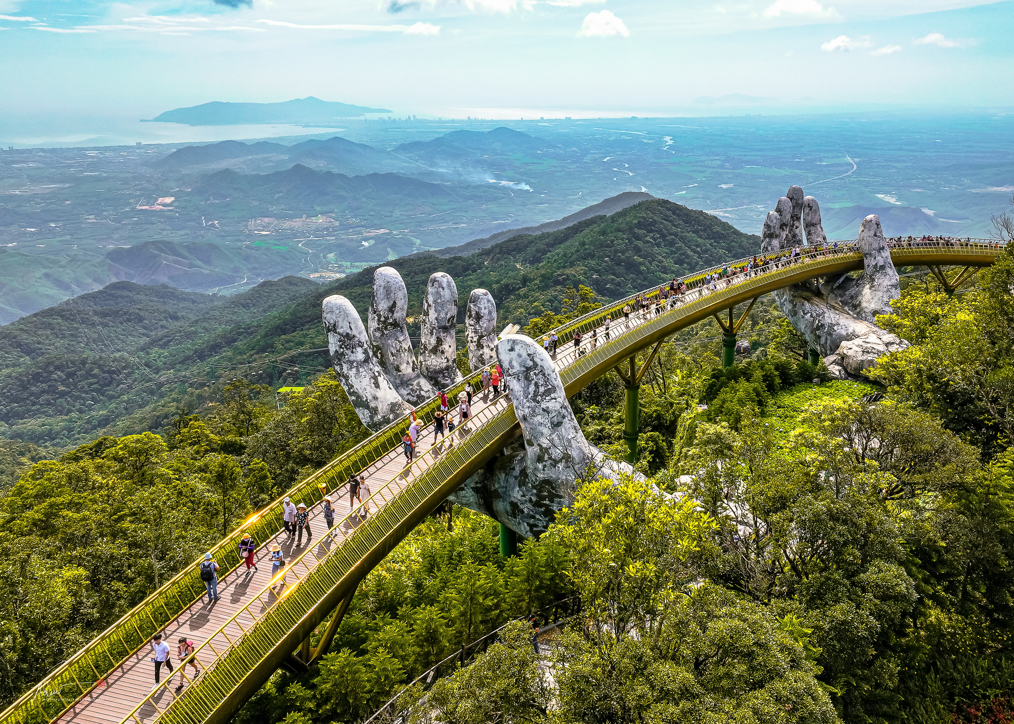 Visitors crossing the Golden Bridge at Ba Na Hills near Da Nang, its walkway held aloft by two giant stone hands.